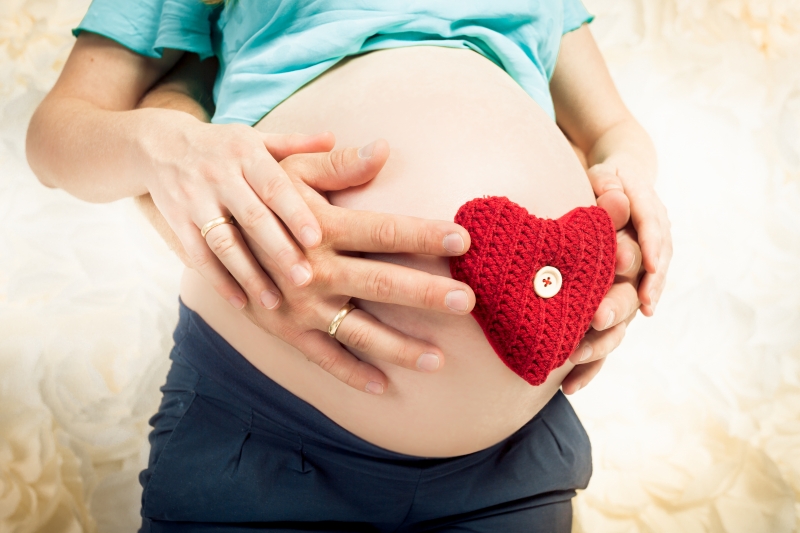 12527937-caring-and-loving-expectant-parents-holding-red-heart-on-abdomen